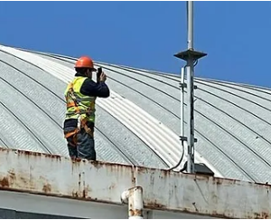 Trabajador inspeccionando un sistema de protección contra rayos en un tejado